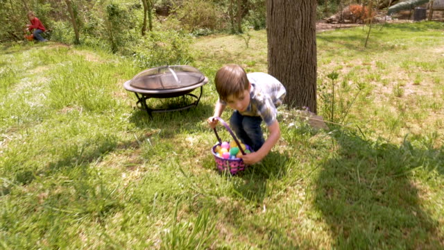 Young-male-child-standing-up-holding-a-basket-of-Easter-eggs-in-slow-motion