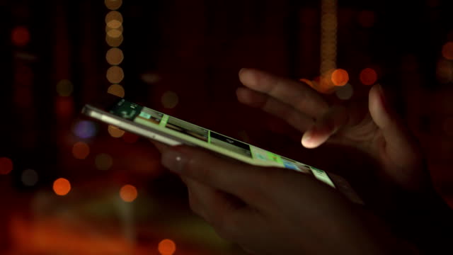 Primer-plano-de-manos-de-la-mujer-utilizando-smartphone-con-pantalla-táctil-al-aire-libre-en-la-ciudad-en-la-noche.-Navegación-por-messenger