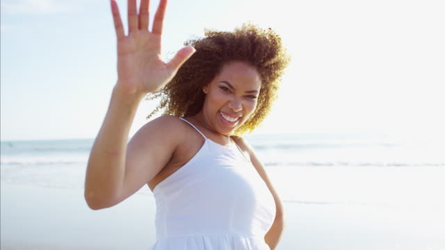 Portrait-of-African-American-female-waving-by-ocean