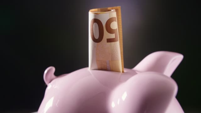 Closeup-Of-Piggybank-With-Currency-Turning-On-Table