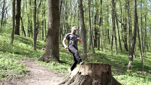 Ein-Mann-springt-auf-einem-großen-Baumstumpf