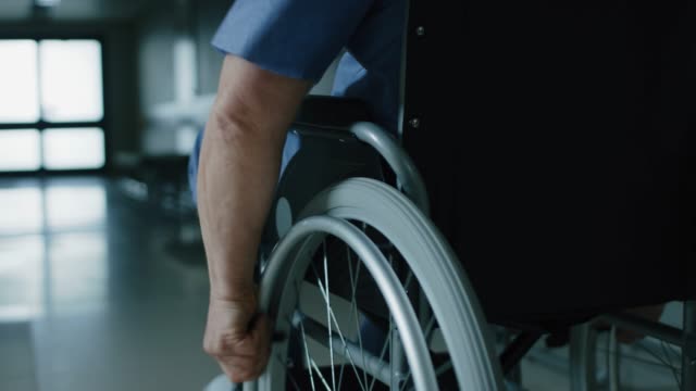 Im-Krankenhaus,-close-up-nach-Schuss-von-der-ältere-Mann-im-Rollstuhl-bewegten-durch-den-Flur.