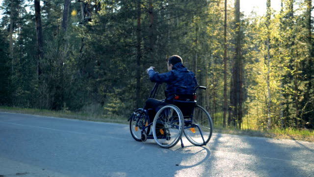 Training-wheelchair-is-getting-moved-along-the-road-by-a-disabled-man