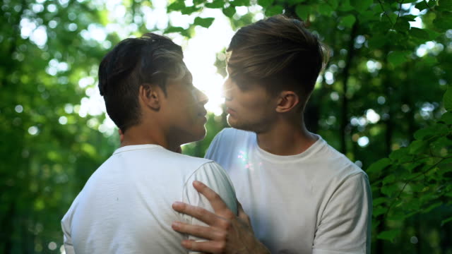 Jóvenes-besándose-y-mirando-unos-a-otros-con-amor,-fecha-en-el-parque,-romance-gay