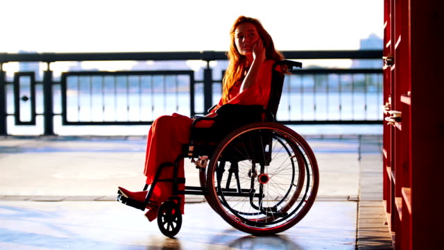 Schönes-rothaarige-Mädchen-im-Rollstuhl-nimmt-aus-dem-Regal-Buch