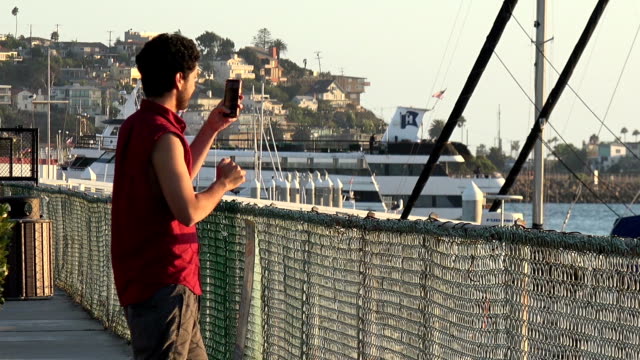 Handsome-tourist-taking-smart-phone-pictures-of-a-marina