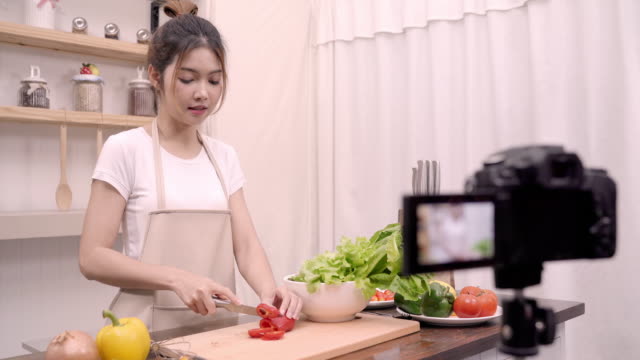 Blogger-Asiatin-mit-Kamera-Aufnahme-wie-gesundes-Essen-Salat-video-für-ihre-Abonnenten,-weibliche-Verwendung-Bio-Gemüse-Salat-vorbereiten-fitten-Körper-zu-Hause-zu-machen.-Gesunde-Ernährung-Konzept.