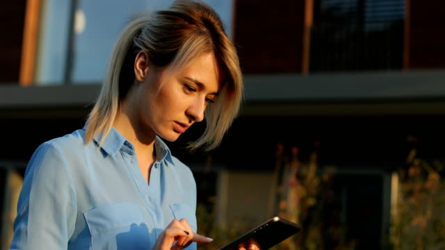 Close-up-portrait-of-a-beautiful-business-woman-holding-and-using-tablet-outside,