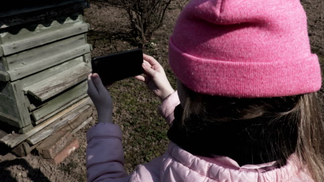 Mädchen-mit-Smartphone-in-der-Nähe-von-Bienenhile