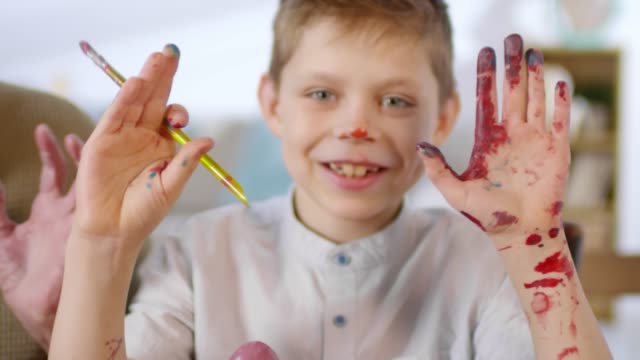 Niño-mostrando-las-manos-cubiertas-de-pintura