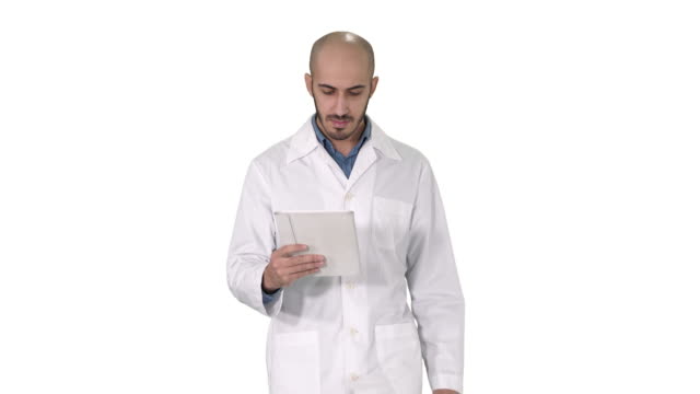 Médico-masculino-maduro-sosteniendo-la-tableta-digital-usando-y-caminando-sobre-fondo-blanco