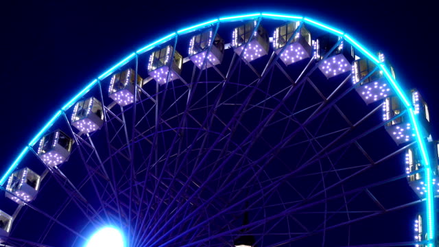 Illuminated-ferris-wheel-rotates-against-a-dark-sky.