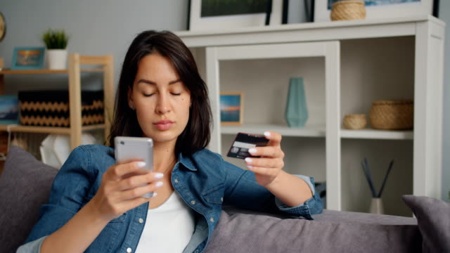 Slow-motion-of-happy-woman-paying-online-with-bank-card-using-smartphone