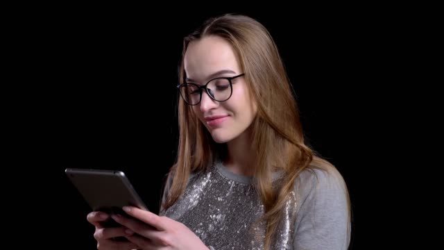 Closeup-shoot-of-young-attractive-hipster-female-in-glasses-using-the-tablet-with-background-isolated-on-black