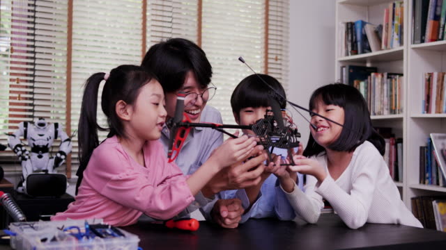 Lehrer-und-Schüler-arbeiten-an-einem-programmierbaren-Roboter-im-Schulwissenschaftsklassenprojekt.-Technologie--und-Bildungskonzept.