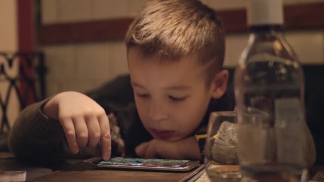 Gelangweilter-Junge-mit-Smartphone-im-Café