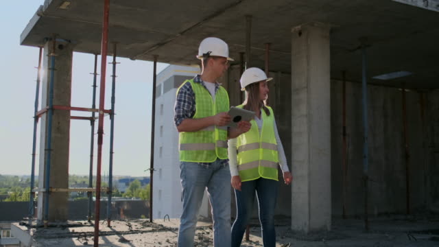 Supervisor-of-a-building-under-construction-man-discussing-with-engineer-designer-woman-the-progress-of-construction-and-examines-a-building-plan