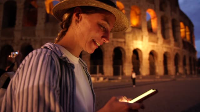 Sonriendo-chica-hipster-cáucaso-satisfecho-con-mapas-en-el-teléfono-inteligente-durante-las-visitas-turísticas-en-Roma-utilizando-la-conexión-4G-y-rutas-de-seguimiento-GPS-y-lugares-notables
