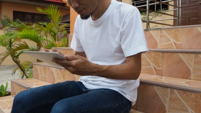 Hombre-sosteniendo-usando-el-juego-de-la-tableta-en-línea-en-casa