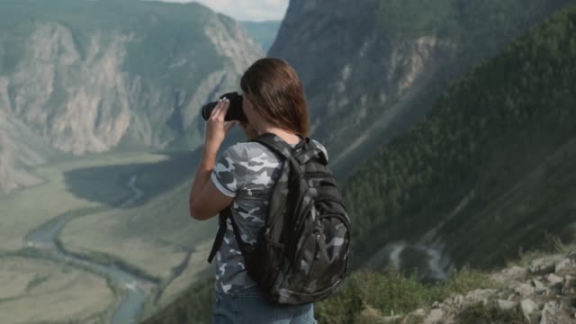 Weibliche-Reisende-macht-schöne-Bilder-mit-der-Kamera,-während-sie-auf-dem-Gipfel-des-Berges-steht.