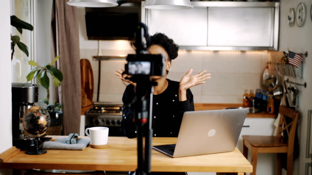 Glückliche-junge-attraktive-afrikanische-Video-Blogger-Aufnahme-neue-vlog-mit-professioneller-Kamera-zu-Hause-Küche-Zeitlupe.