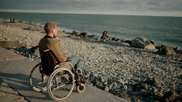 Adult-man-with-paralysis-of-bottom-of-body-is-sitting-in-sea-shore-and-relaxing