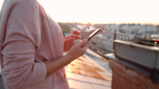 Woman-Using-Phone-on-Building-Roof
