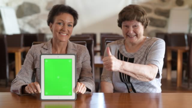 Glückliche-Mutter-und-Tochter-zeigen-digitale-Tablet-zusammen-und-geben-Daumen-nach-oben