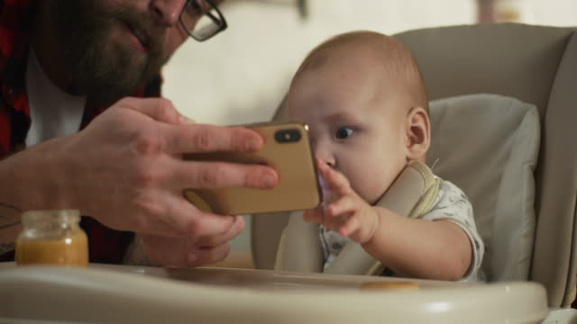 Padre-mostrando-teléfono-inteligente-a-bebé