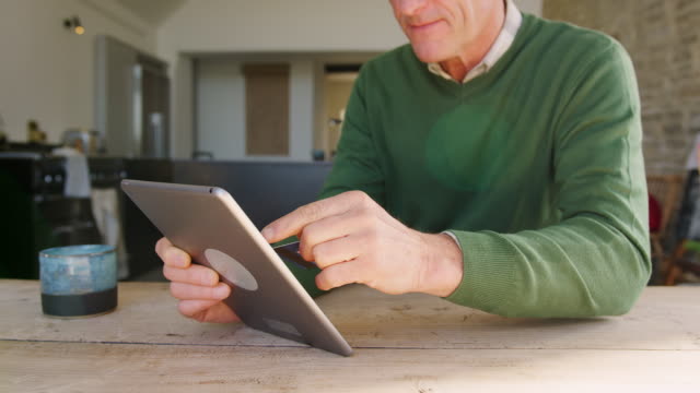 Nahaufnahme-von-Senior-Man-at-Home-Kauf-von-Waren-oder-Dienstleistungen-online-mit-digitalen-Tablet-und-Kreditkarte