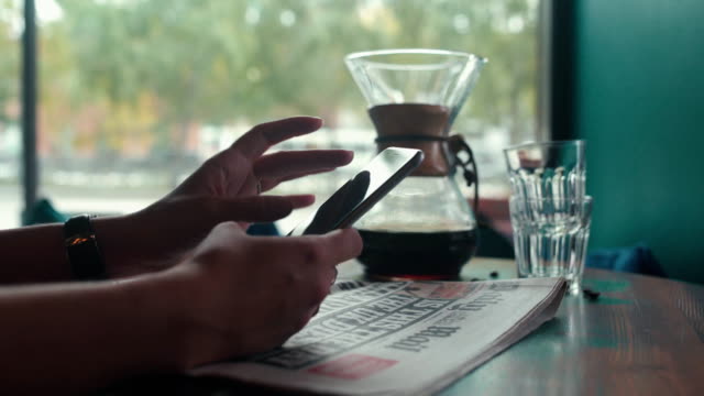 Freshly-brewed-coffee-and-a-newspaper.-Woman-with-cell-phone