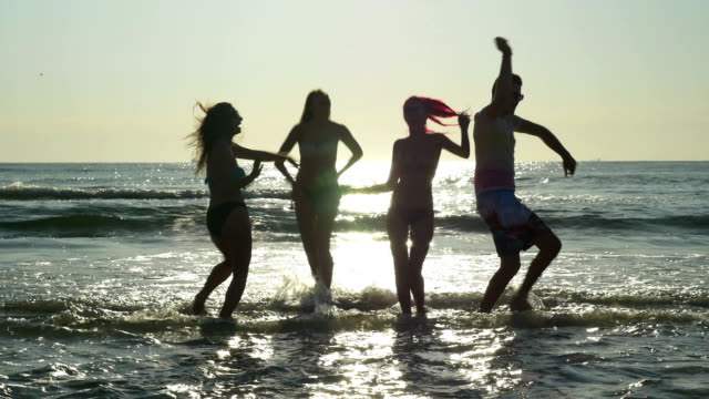 Gruppe-von-vier-Freunden-tanzen-am-Ufer-des-Meeres