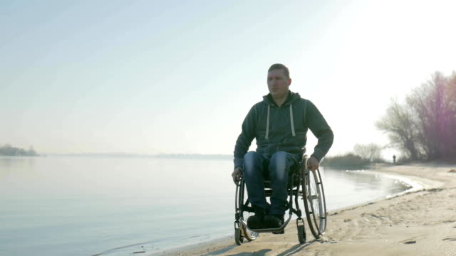 Disabled-man-goes-to-embankment-along-sea-in-wheelchair,-portrait