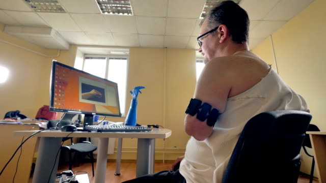 Low-angle-of-the-man-with-the-aputated-left-arm-using-computer.-4K.
