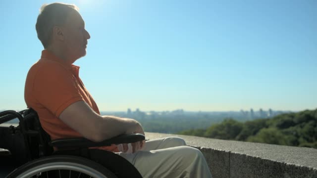 Hombre-wheelchaired-concentrado-agradable-disfrutar-de-la-ciudad-de-observación-del-punto