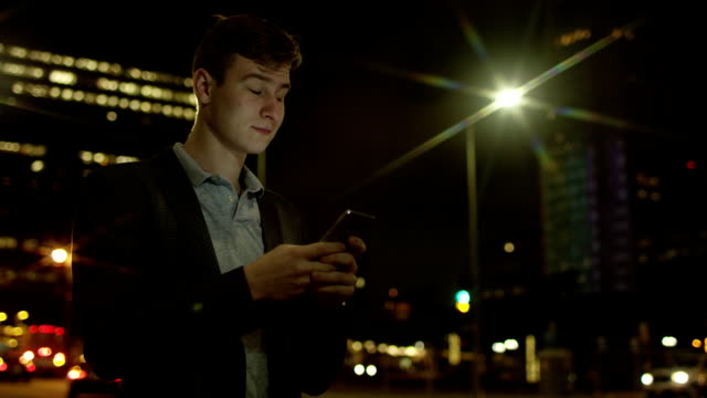 Hübscher-Kerl-ist-eine-SMS-Nachricht-beim-stehen-auf-einer-Straße-eingeben.