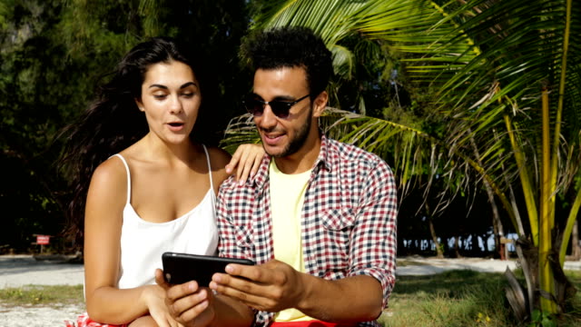 Pareja-con-celular-inteligente-toma-foto-Selfie-al-aire-libre-bajo-las-palmeras-en-la-playa,-feliz-sonriente-hombre-y-mujer