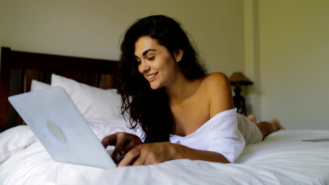 Mujer-joven-con-Laptop-computadora-feliz-riendo-hermosa-chica-acostado-en-cama-en-dormitorio-por-la-mañana