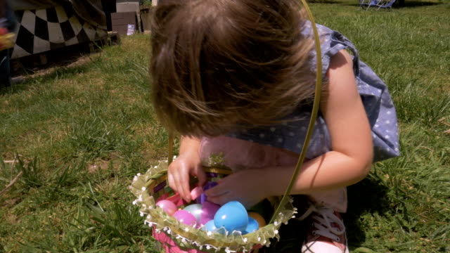 Adorable-little-girl-opening-a-piece-of-candy-from-her-Easter-basket
