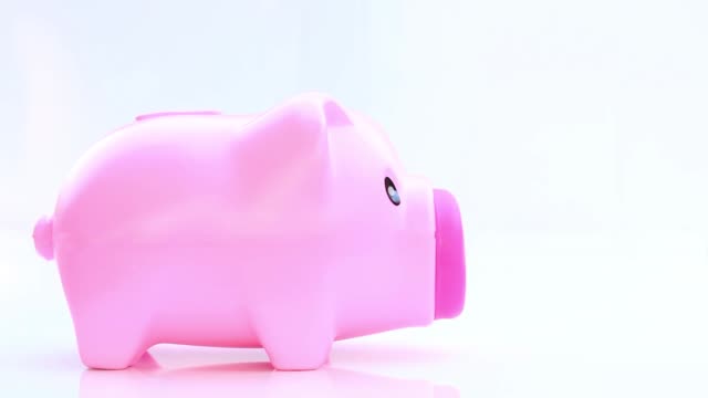 Hand-putting-a-coin-into-the-piggy-bank-on-white-background.-Saving-money-concept,