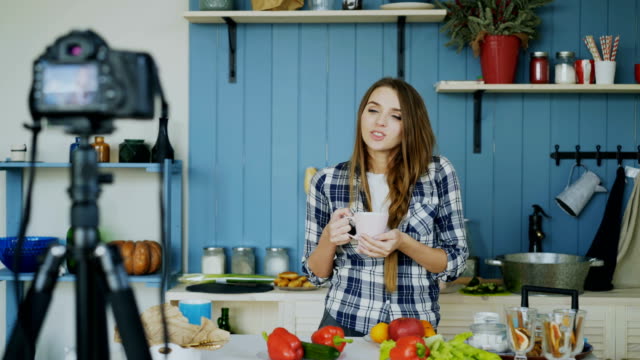 Young-attractive-woman-recording-video-food-blog-about-cooking-on-dslr-camera-in-kitchen