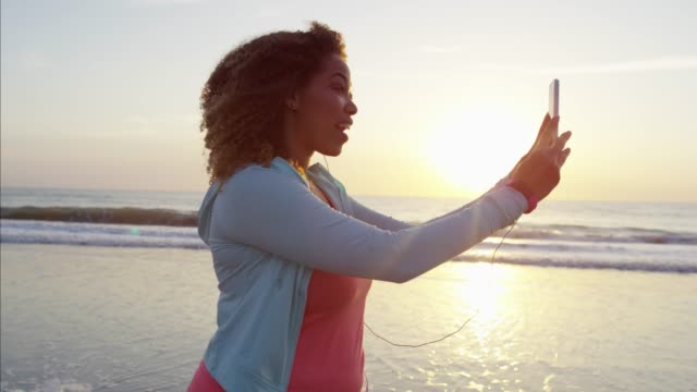Ethnic-female-videoing-on-smart-phone-by-ocean