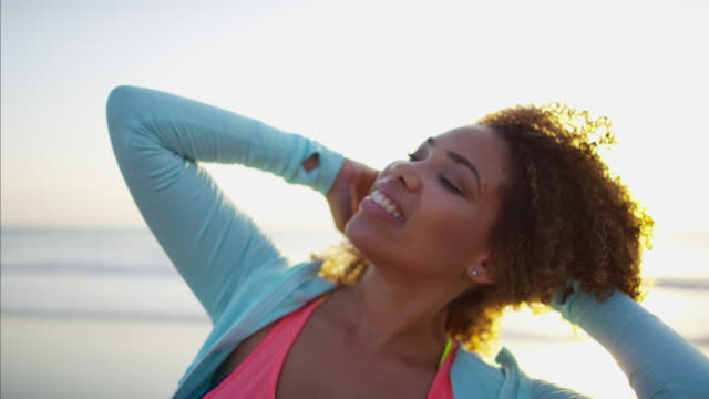 Afroamerikanische-Frau-entspannt-am-Strand-bei-Sonnenaufgang