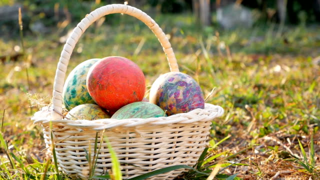 Close-up-of-basket-with-colourful-a-easter-eggs-on-grass-in-sunshine-background