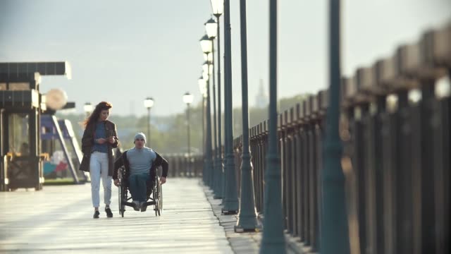 Hombre-discapacitado-en-silla-de-ruedas-caminar-juntos-a-su-novia-en-el-muelle