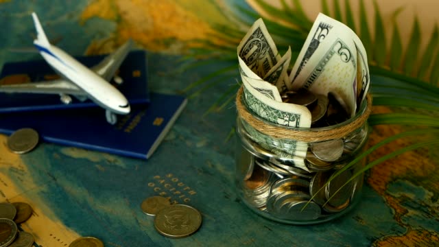 Concepto-de-presupuesto-de-viaje.-Dinero-ahorrado-para-las-vacaciones-en-tarro-de-cristal-en-el-fondo-de-mapa-del-mundo