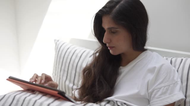 young-woman-reading-a-book-on-a-modern-portable-tablet-and-smiling