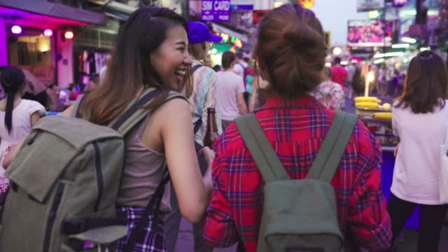 Viajero-mochilero-mujeres-asiáticas-lesbianas-lgbt-par-de-viajes-en-Bangkok,-Tailandia.-Mujer-bebiendo-alcohol-o-cerveza-en-el-Khaosan-Road-la-calle-más-famosa-de-Bangkok.