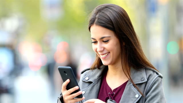 Happy-teen-browsing-on-phone-in-the-street