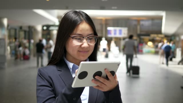 Empresaria-asiática-trabajando-en-una-tableta-digital-en-el-aeropuerto